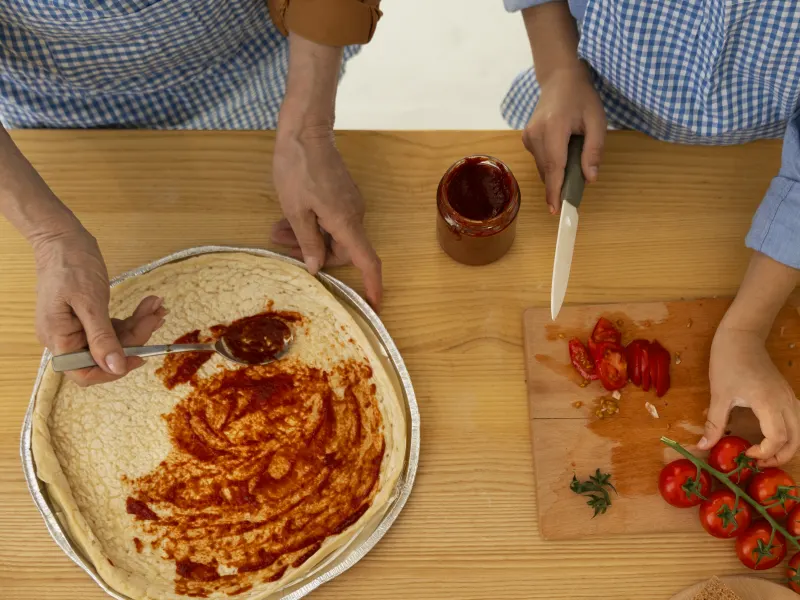 Dos personas preparando una pizza juntas